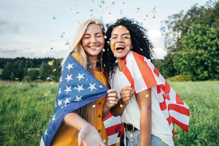 Two happy women covered by the USA flag