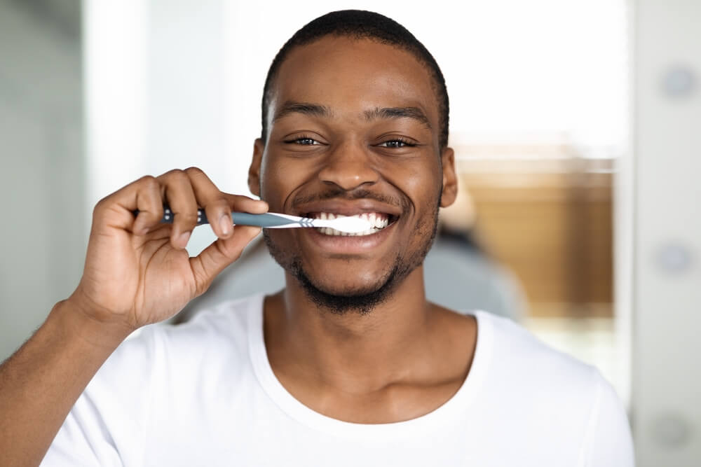 Joyful African American Guy Brushing Teeth With Toothbrush