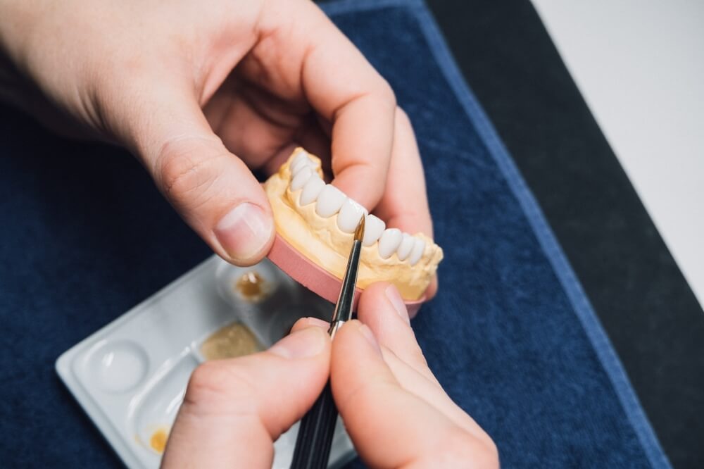 Dental technician or dentist working with tooth dentures model