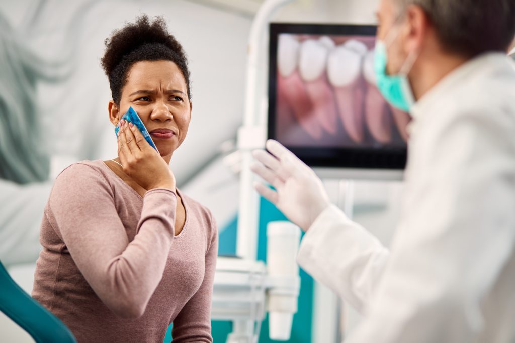 woman holding mouth in pain from working with an unqualified dentist, dentist in the foreground